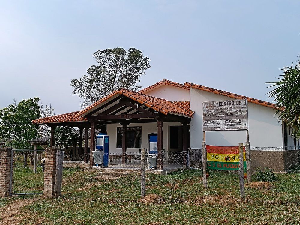 Puesto de salud rural en Bolivia, con techo de teja y bandera boliviana
